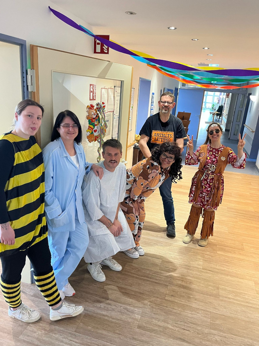 Verkleidete Mitarbeiter und Mitarbeiterinnen des Paul Marien Hospizes stehen auf einem Flur.