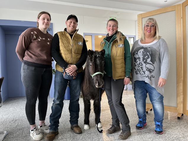 Shetlandpony Lena steht zwischen vier Personen am Flur des Paul Marien Hospizes.